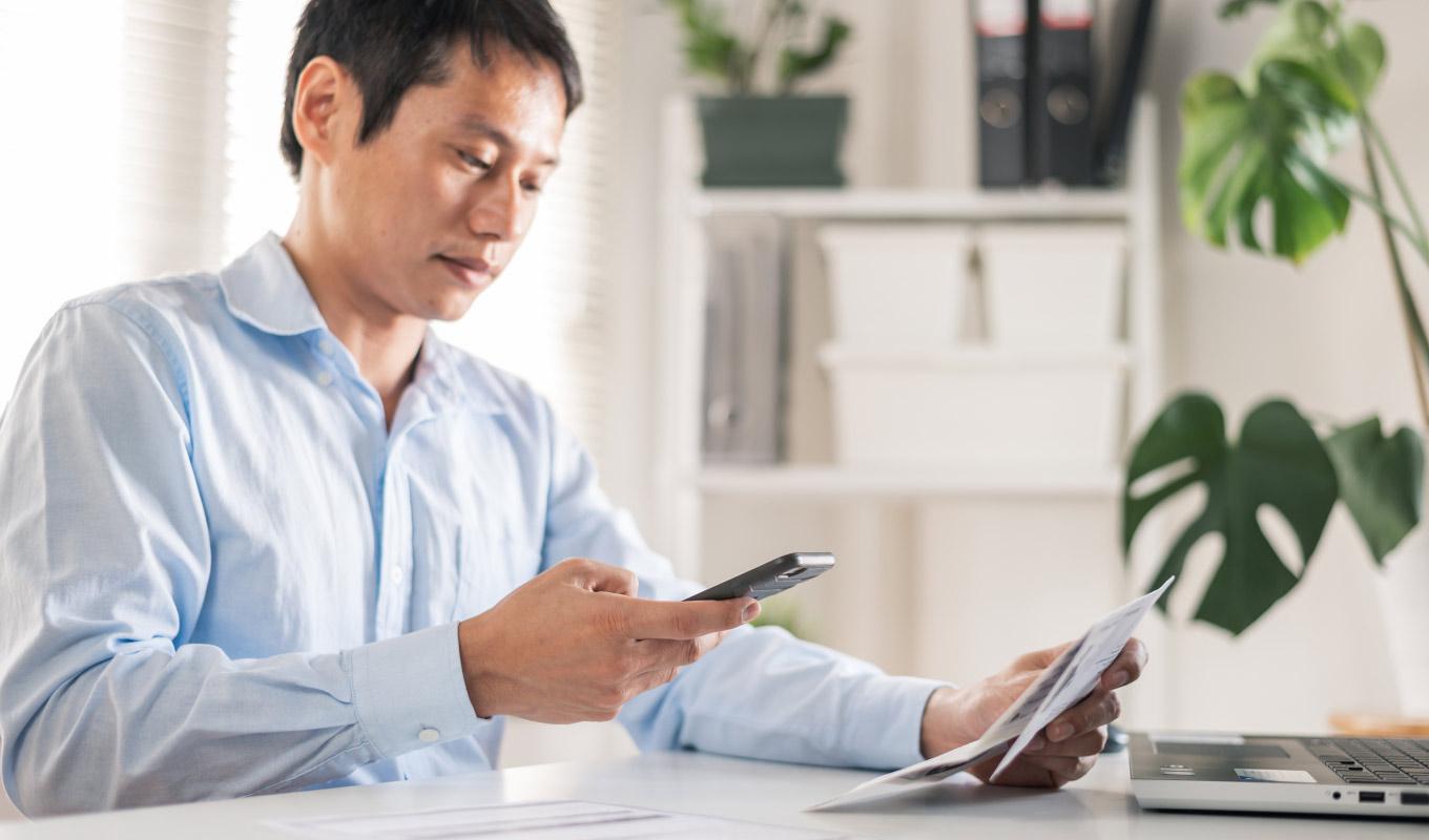 professional comparing a hard copy document to data on a mobile phone